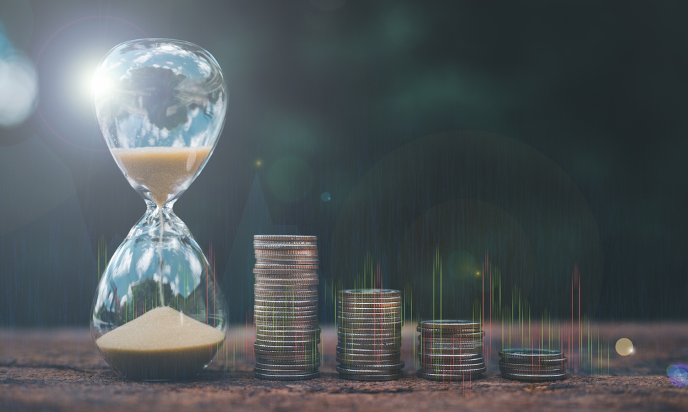Hourglass next to ascending stacks of coins on a dark background, representing long-term wealth planning for a Lake Macquarie client