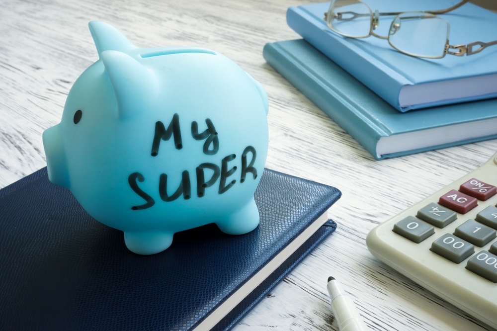 Blue piggy bank labelled 'My Super' sitting beside notebooks, reading glasses and a calculator, illustrating superannuation advice for a Port Stephens client