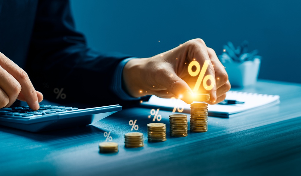 Hand stacking coins beside a calculator with glowing percentage symbols overlaid, representing investment growth for a Hunter Valley client