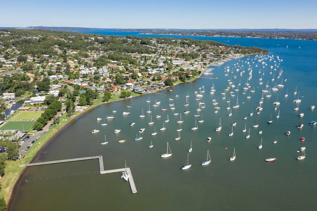 Aerial view of Lake Macquarie foreshore with yachts moored across the bay and lakeside homes along the shoreline