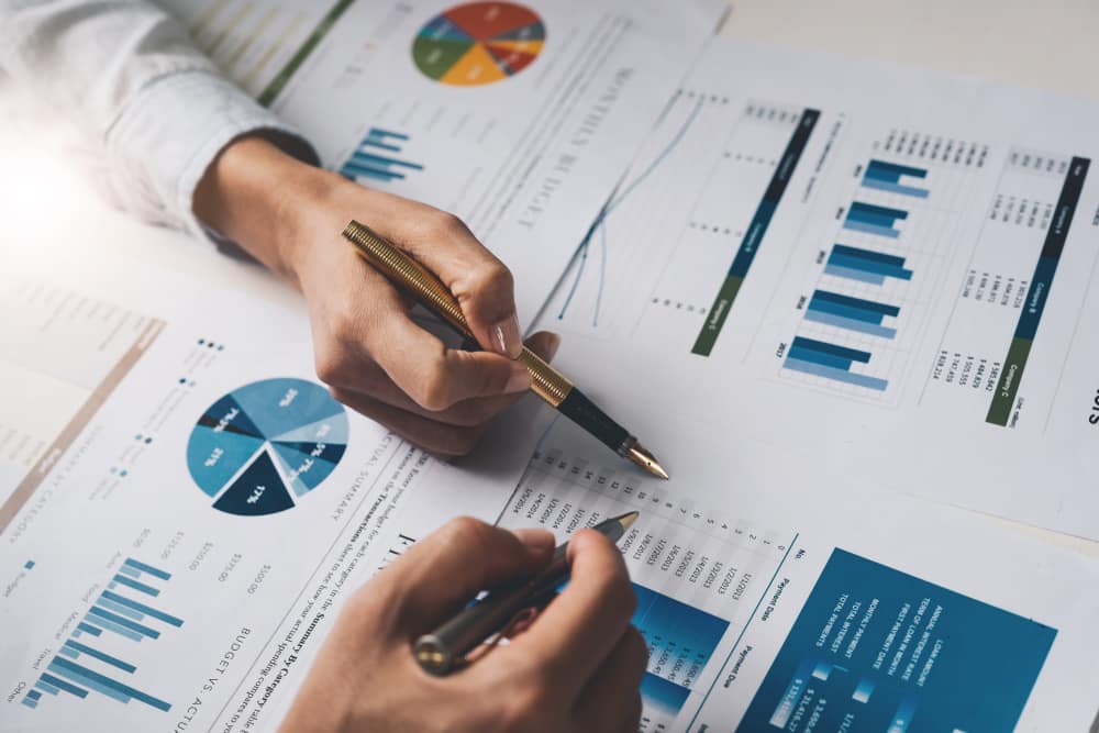 Hand holding a pen over printed investment charts during a Hunter region portfolio review